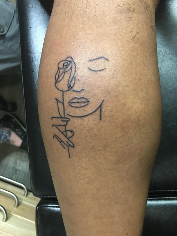 男生小腿上黑色简单线条人物和植物花朵纹身图片